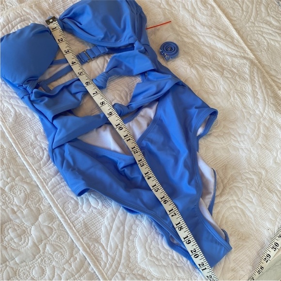 One-piece swimsuit laid flat with a measuring tape across the garment